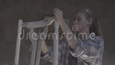 这个女孩在一个<strong>木工</strong>车间工作，擦家具。